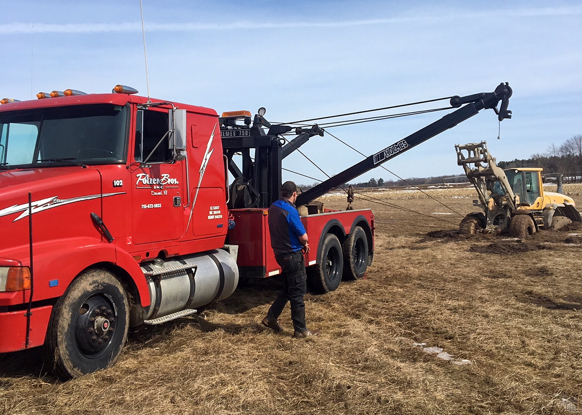Red Polzer Tow Truck pulling tractor out of mud field