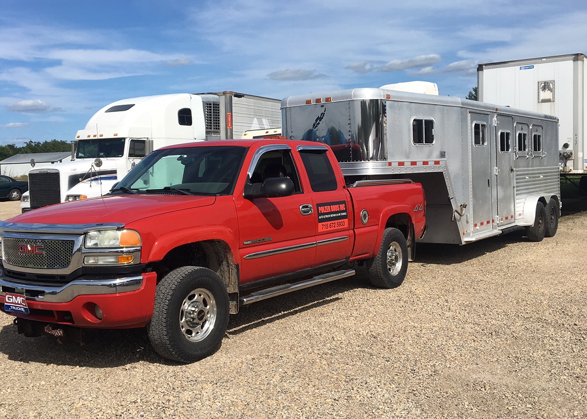 Red Polzer GMC truck pulling horse trailer for long haul